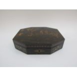 A Japanned canted form lacquered box opening to reveal segmented interior with marbled paper lining,