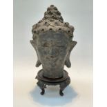 A terracotta bust of a deity on a carved wooden stand, some damage, 40cm tall total
