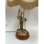 A figural lamp of two herons on wooden base