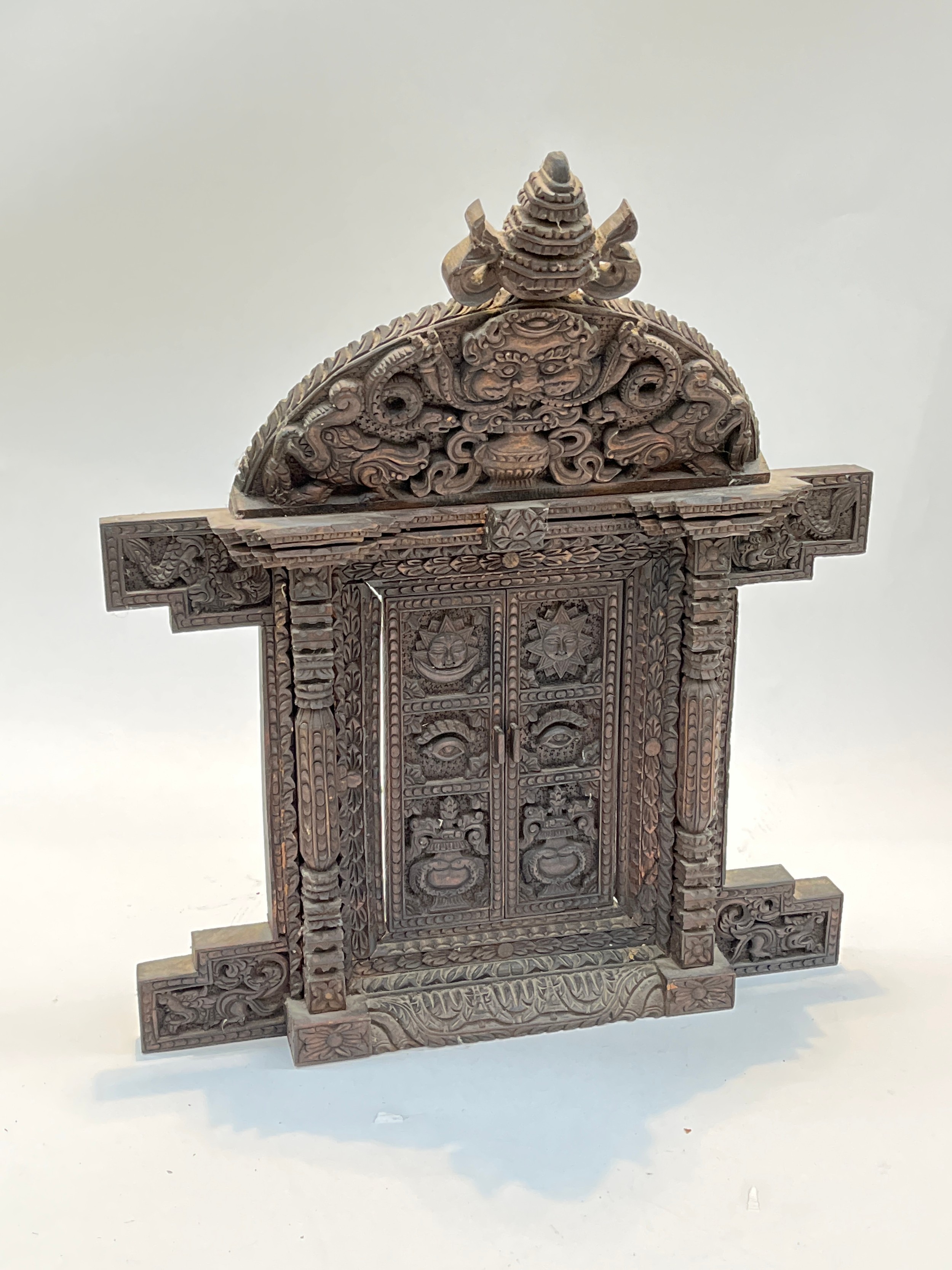 A carved wood decorative table top doorway from Kathmandu, Nepal, 46cm tall