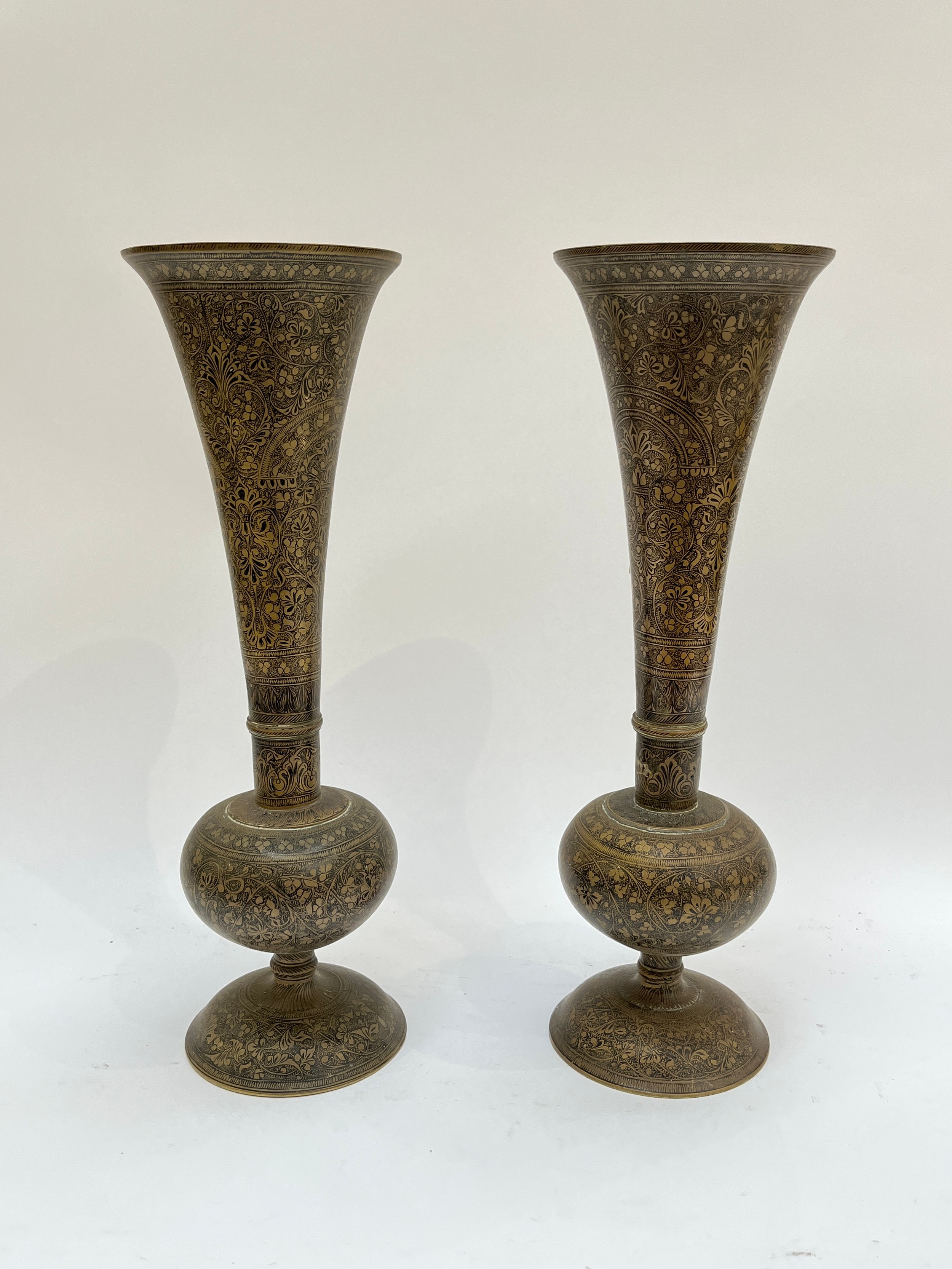 A pair of Middle-Eastern brass trumpet-form vases with all-over foliate pattern, 36cm tall
