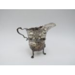 A T. Hill silver repoussé milk jug on three legs, decorated with ducks, fox, swan and dolphin,