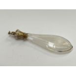 A continental white metal and cut glass scent bottle of faceted teardrop form, the lid surmounted by
