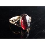 A rose gold ring set with an oval cabochon garnet in open shoulders, unmarked. Size K, 2.7g