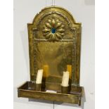 An Arts and Crafts wall hanging double candle sconce with brass arched back plate with hammered