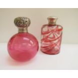 Two glass scent bottles, one cranberry with embossed silver lid, the other with swirled red and