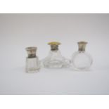 Three silver topped glass scent bottles, two with yellow guilloche lids