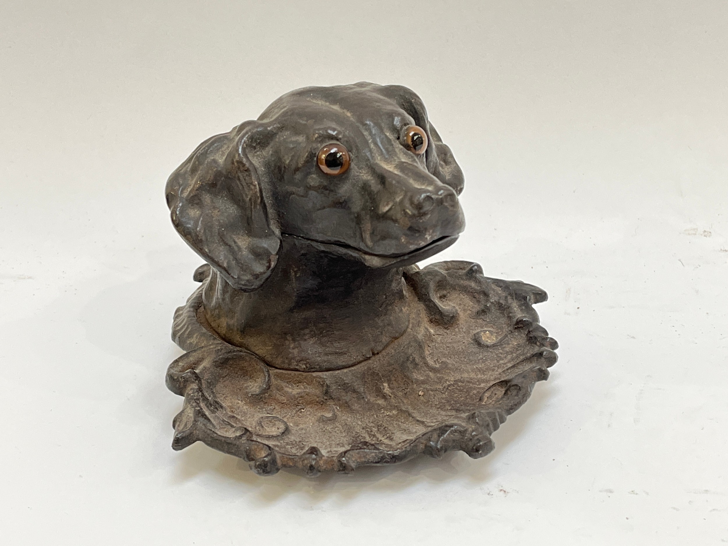 A Victorian cast iron dog head shaped inkwell with glass inset eyes and lead liner