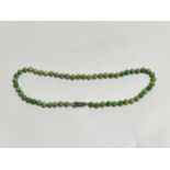An Art Deco green jade necklace with silver and marcasite clasp