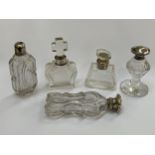 Five clear glass scent bottles, one with cross-form stopper, white metal and silver fittings