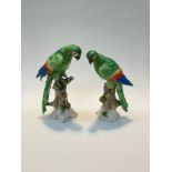 A pair of Samson porcelain models of parrots, each perched upon tree stumps, green enriched with