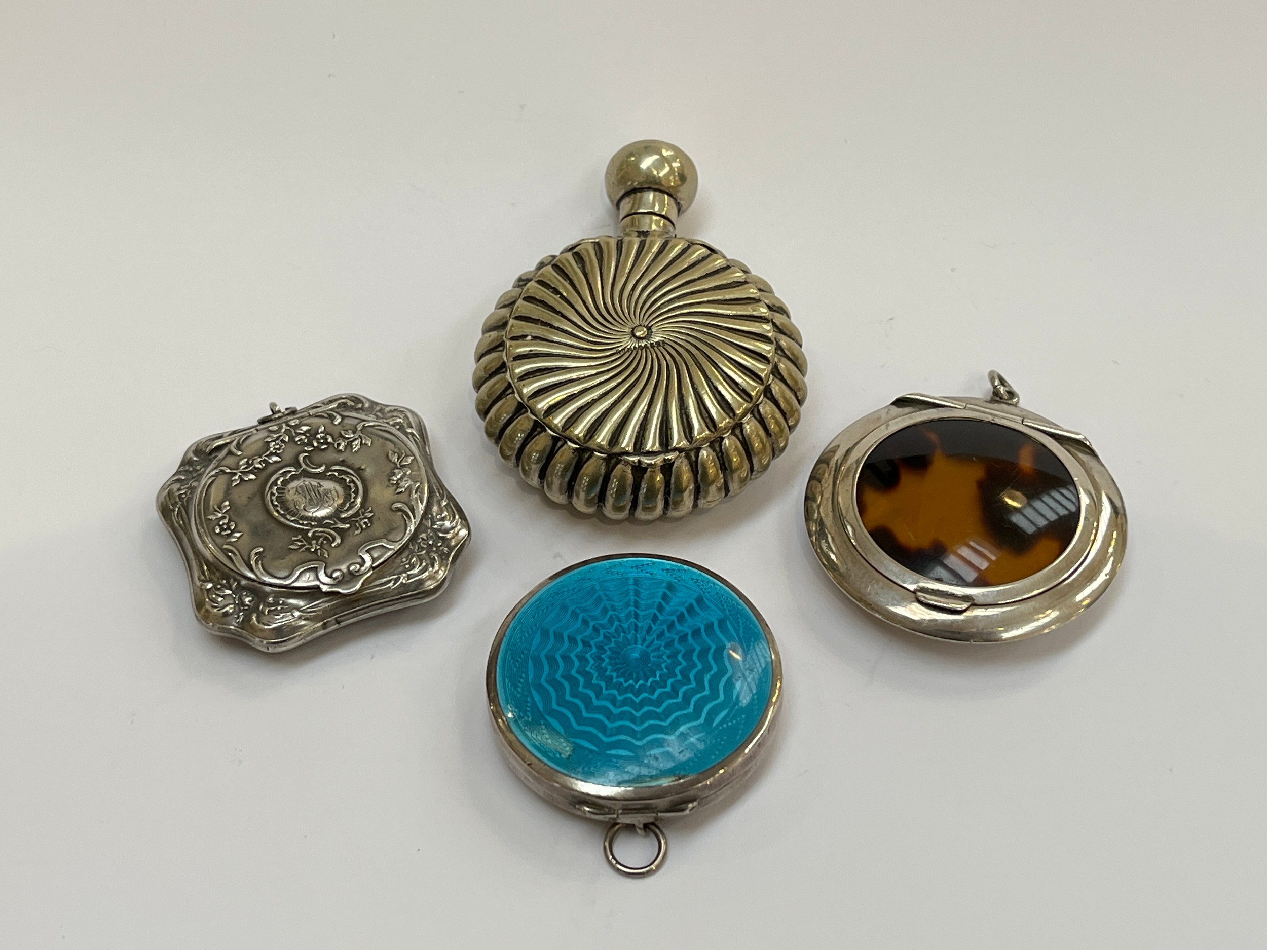 Three silver powder compacts, one with blue guilloche lid, together with a base metal example (4)