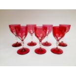 A set of seven Edwardian cranberry and clear slice cut wine glasses