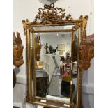 A 19th Century French gilt wood and gesso wall mirror, ribbon and basket of foliage crest, faceted