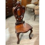Circa 1840 a Cuban mahogany hall chair with carved scroll back rest over a serpentine front flat