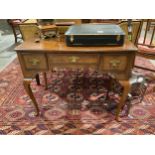 A walnut lowboy with feather cross banded decoration the three frieze drawers over a shaped apron on