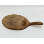 A Robert Thompson (Mouseman) oak cheeseboard with carved mouse detail to surface, 38cm length