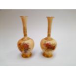 A pair of Royal Worcester peach ground bottle vases, 16.5cm tall