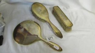 A silver backed hand mirror, two silver backed brushes, monogrammed M.