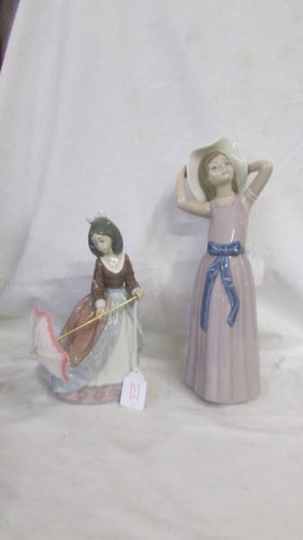 A Lladro figure of a girl with a parasol and another of a girl in hat.