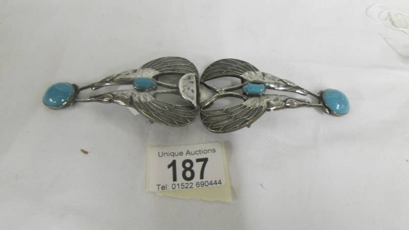 An arts and crafts white metal belt buckle with turquoise stones in the form of a styalised bird.