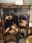 A Japanese lacquered four fold dressing screen decorated with storks. Each panel 183.5cm x 40.5cm