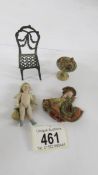 A miniature 19th-century doll, another miniature doll, a mini bird bath and a mini metal chair.