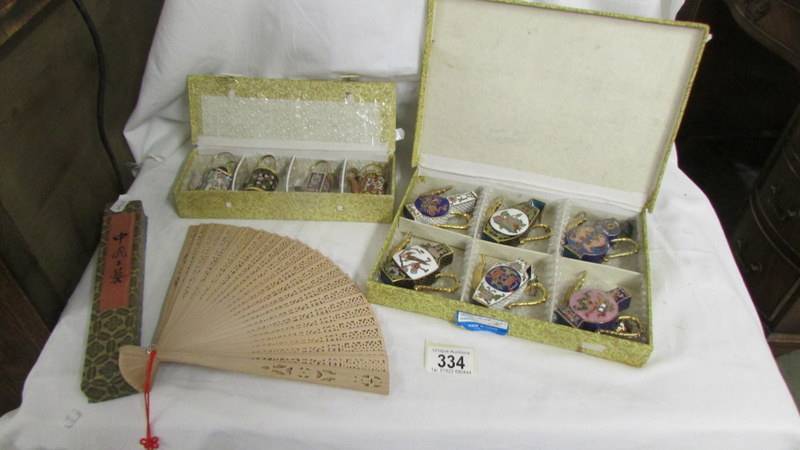 Two cased sets of Chinese Cloissonne tea/coffee pots and a boxed fan.