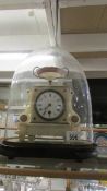 An alabaster clock under glass dome.