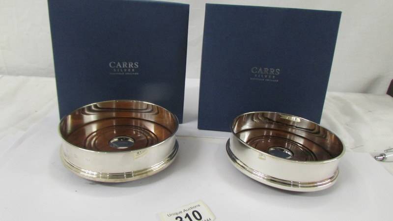 A boxed pair of Carr's hall marked silver wine coasters. Both in as new condition