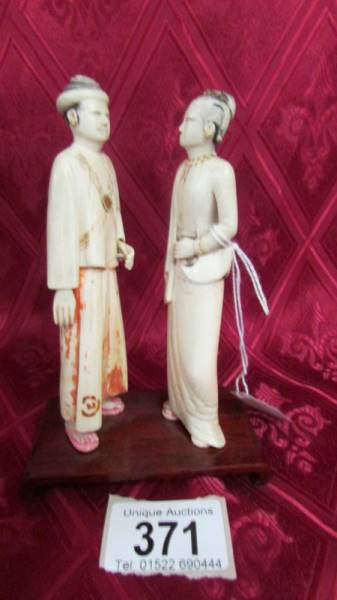 A pair of antique carved ivory figures on a wooden base. Neither figures have any damage but have