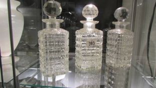 A set of three heavy cut glass decanters.