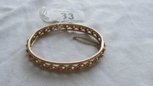 A gold bangle with safety chain, 12.4 grams.