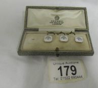 An Asprey set of three studs (one missing) in mother of pearl with centre diamond, platimum
