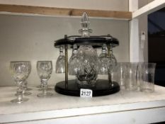 A decanter & glasses on wooden stand & 2 sets of 6 glasses. Collect only.