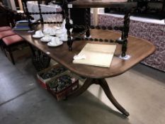A dark wood stained extending dining table on twin tripod base with brass lion paws feet