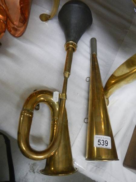 A brass car horn and one other brass horn.