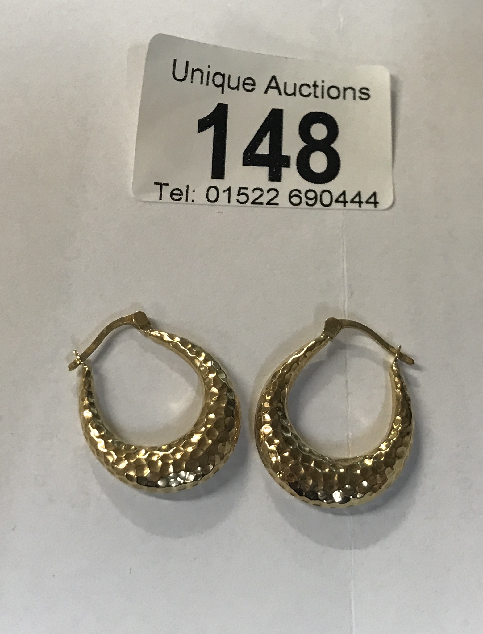 A pair of gold hoop earrings in a textures 9ct gold, stamped.