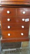 A miniature 2 over 3 chest of drawers with porcelain knobs.