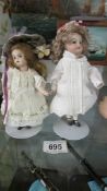 Two small porcelain dolls on stands.