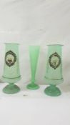 A pair of hand decorated green glass vases and one other. Collect only.