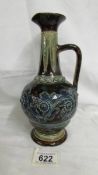 An 1875 Doulton Lambeth 9" George Tinworth narrow necked jug with handle. Decorated with brown, blue