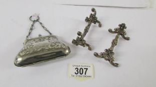 A silver plated purse and a pair of ornate knife rests.
