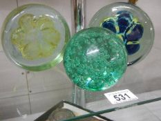 Three large glass paperweights.