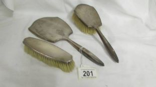 A silver backed hand mirror with two matching brushes.