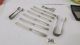 Six silver handled butter knives, two silver sugar tongs and a white metal sugar tongs.