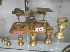 A set of brass postal scales with weights and another set of brass weights.