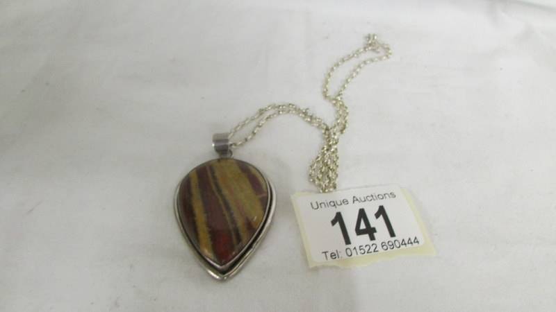 A jasper stone pendant in a silver mount in a heart design on an attached silver chain.