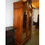 A double door French armoire having beveled mirror doors, heavily carved frieze and on carved