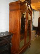 A double door French armoire having beveled mirror doors, heavily carved frieze and on carved
